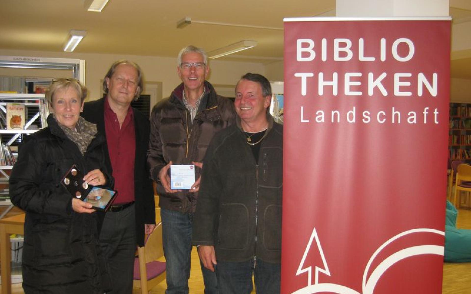 Vier Personen links neben dem Rollup mit Aufdruck "Bibliotheken Landschaft"